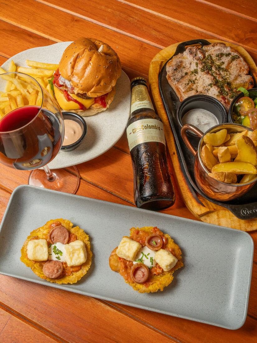 Mesa de restaurante con hamburguesa, carnes y bebidas