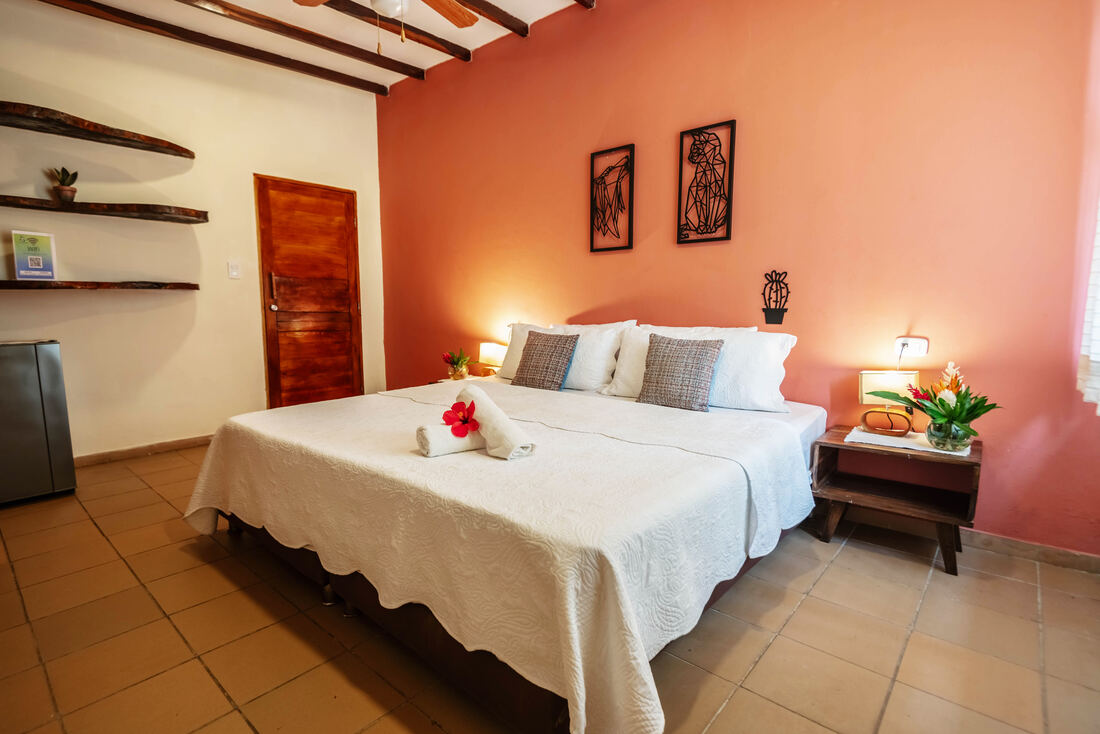 Habitación de hotel con pared naranja y detalles tropicales